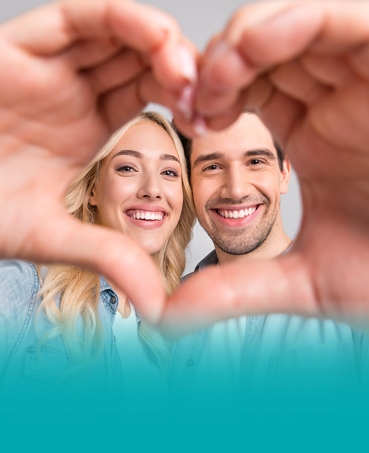 Due donne sorridono rivolte verso l'obiettivo mentre insieme con le mani formano un cuore